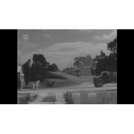 A dust-control truck and another being loaded with aggregate