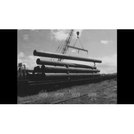 Large pipes are unloaded from a train