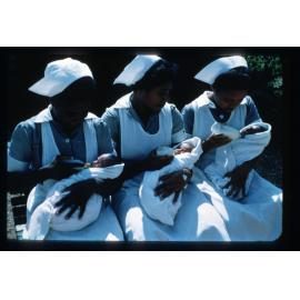 Papuan nurses bottle feeding triplets