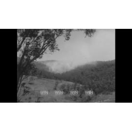Bushfire in a gully and smoke near homes